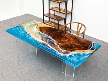 A wooden table with a resin ocean design and clear legs.