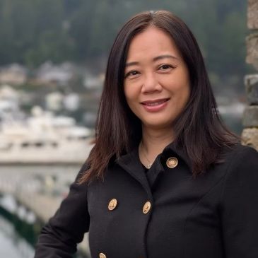 Smiling woman in black coat outdoors.