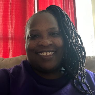 Smiling woman with braided hair and a purple shirt.