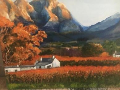 Autumn landscape with mountains, colorful trees, and white houses.