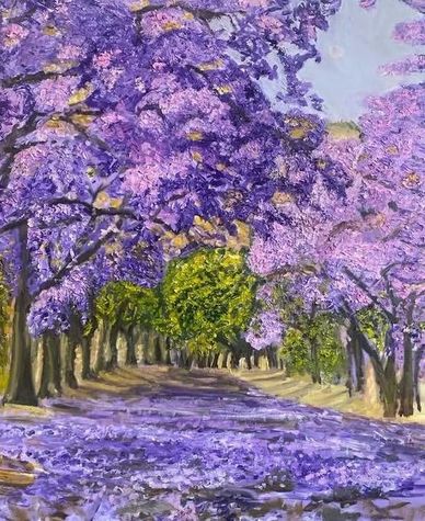A path surrounded by trees with purple blossoms.