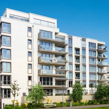 Modern apartment building with balconies under a clear blue sky.