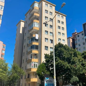 Güneşli hava ve ağaçlar ile sarılı 8 katlı apartman.
