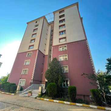 Yüksek katlı bina ve çevresindeki ağaçlar.
