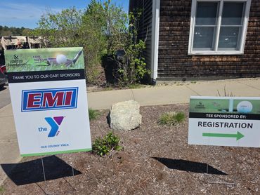 Signs at a golf event showing sponsors and registration direction.