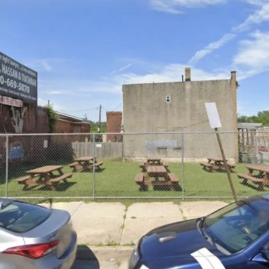 Empty picnic area behind a chain-link fence in an urban setting.
