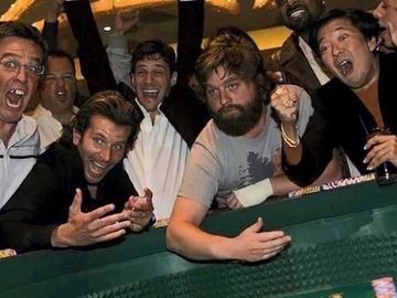 Group of men excitedly playing craps at a casino table.