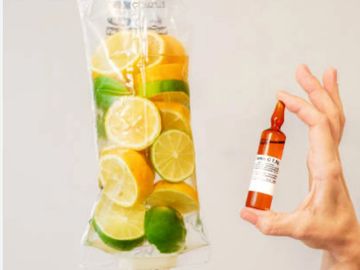 IV bag filled with citrus fruits and a hand holding a small medicine vial.