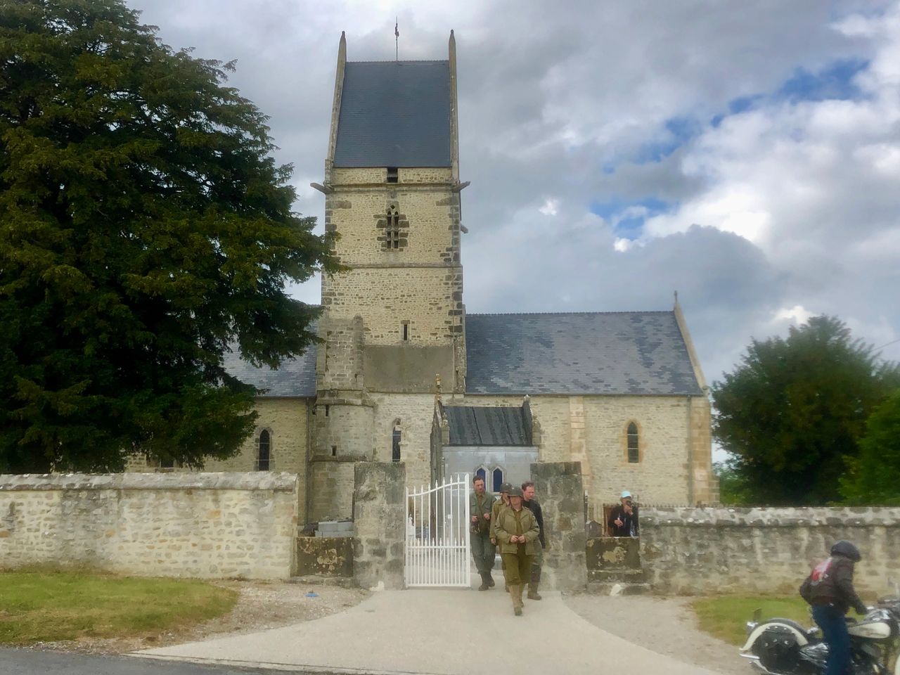 The small village church in Angoville au Plain with American GI re-enactors exiting the grounds around the 75th anniversary of D-Day. The small village church in Angoville au Plain with American GI re-enactors exiting the grounds around the 75th anniversary of D-Day.