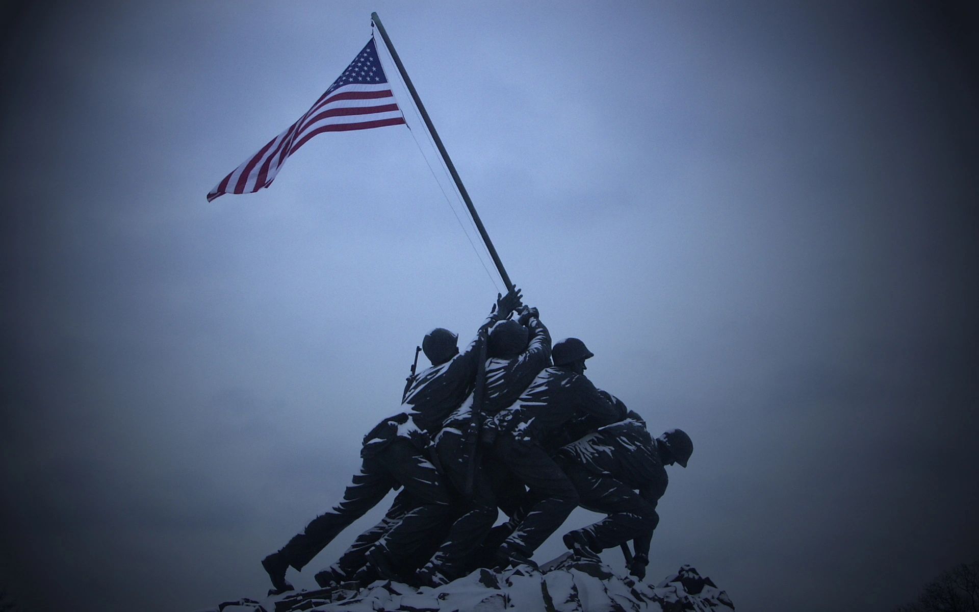 Statue of soldiers raising the American flag against a cloudy sky.
