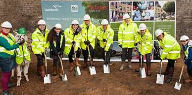 People in wearing high-viz jackets with spades in a row digging.