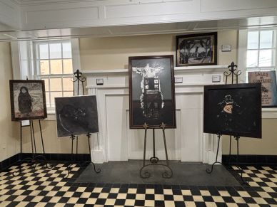 Art display with four framed pieces on easels in a checkerboard-floored room.