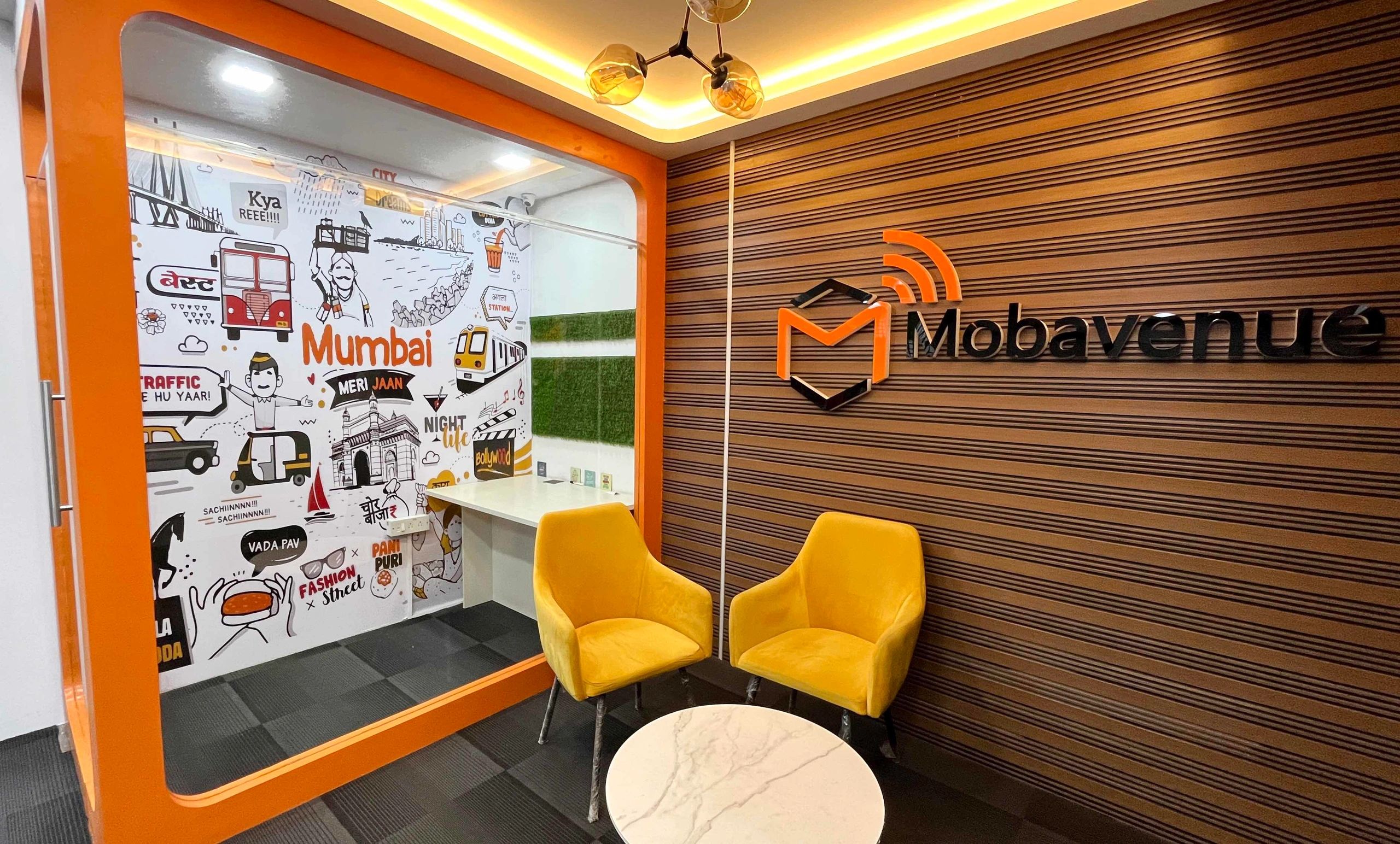 Modern office lounge with vibrant yellow chairs and Mumbai-themed wall art.