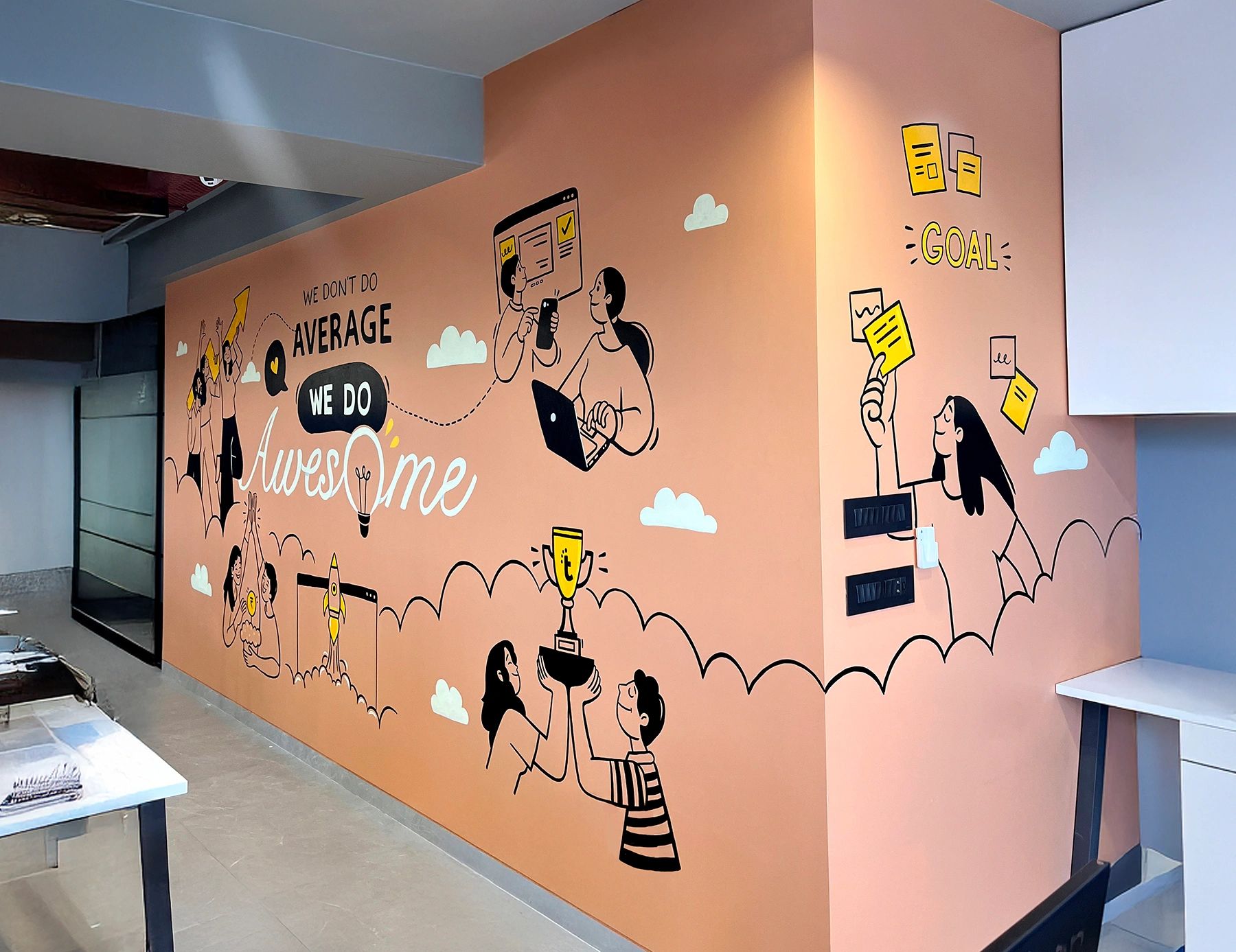 A motivational mural with cartoon figures and inspiring words on a peach wall corner.