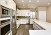 Glossy white Euro cabinets, White speckled engineered quartz counter tops, glass tile backsplash and porcelain "wood" tile" 