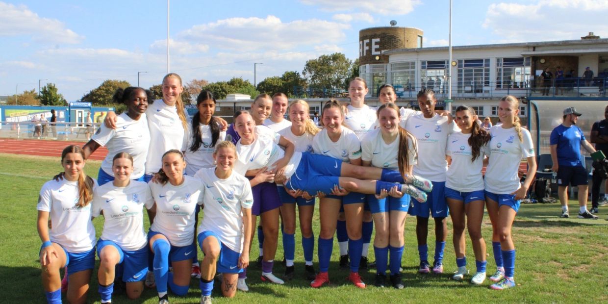 Women soccer team posing for a group photo on a field.