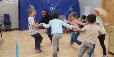 Children playing and holding hands in a circle indoors.