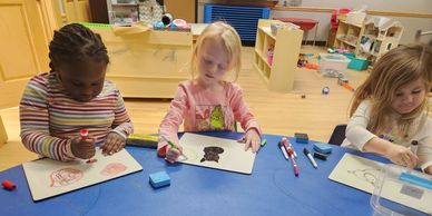 Three kids drawing at a table.