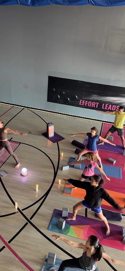 Group yoga class practicing warrior pose indoors.