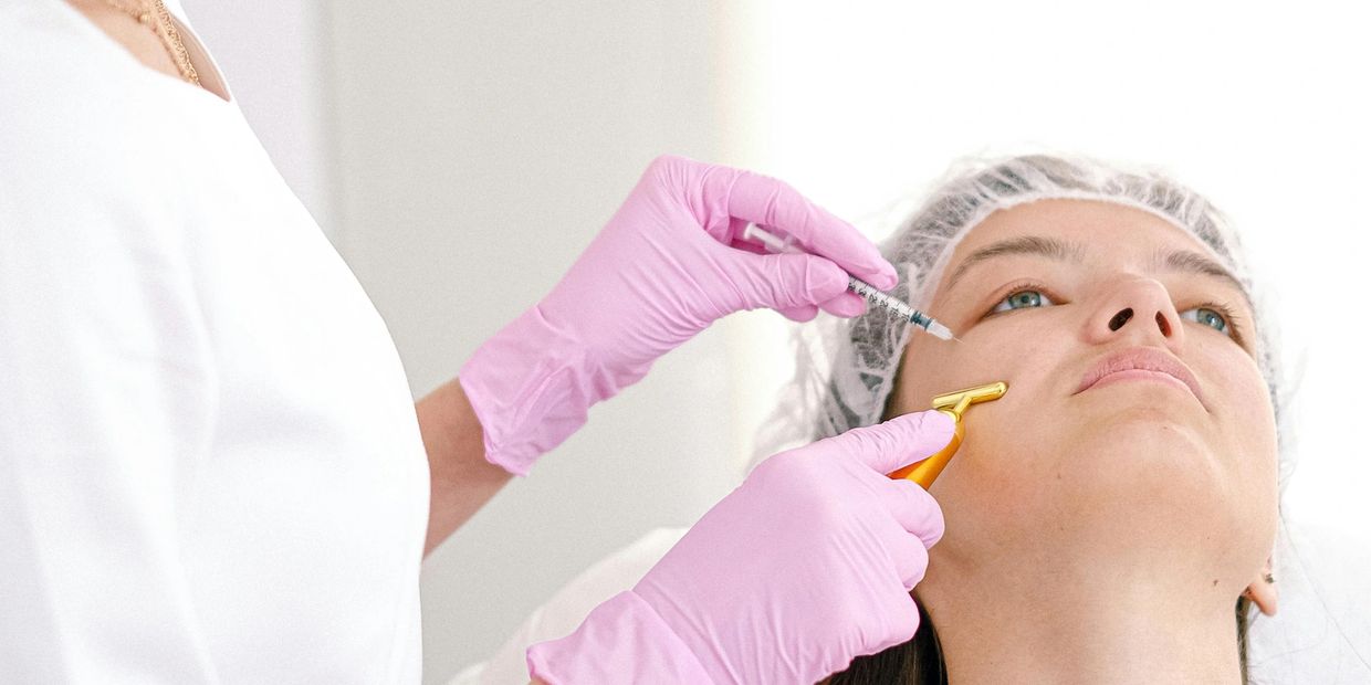 Medical professional administering cosmetic injection to woman's face.