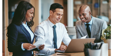 Three colleagues happily discuss a project at work.
