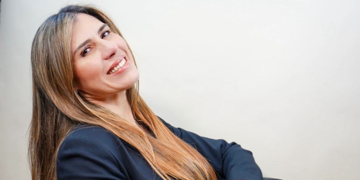 Smiling woman in black blazer leaning back on a chair.