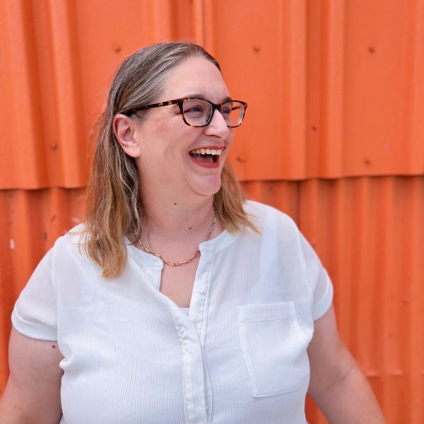 Woman laughing against an orange wall.