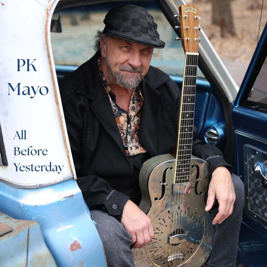 Man with guitar sitting in a vintage car, album cover for PK Mayo's "All Before Yesterday."