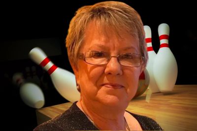 Woman standing in front of bowling pins.