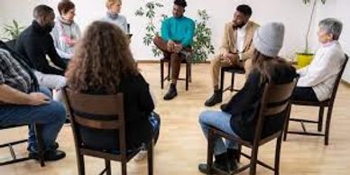 A diverse group of people sitting in a circle during a group therapy session.