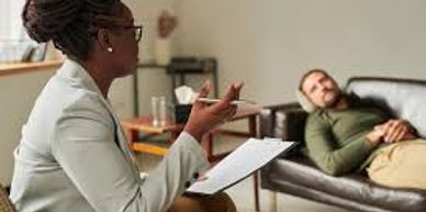 Therapist listening to patient on couch in therapy session.