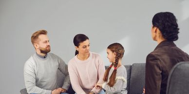 A family therapy session with parents, child, and therapist in a calm setting.
