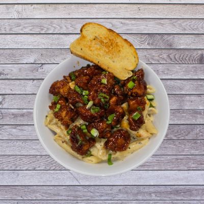 Bowl of Alfredo topped with Bourbon Street chicken and garlic bread.