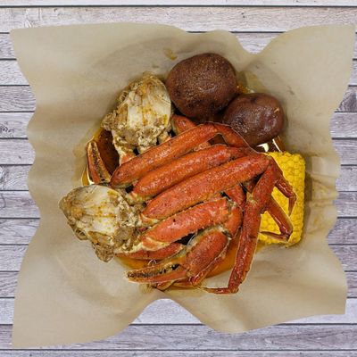 A seafood boil with crab legs, potatoes, and corn.