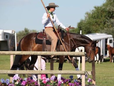 Person riding a horse in an outdoor area with flowers.