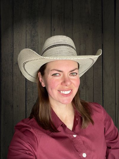 Smiling woman wearing a white cowboy hat and maroon shirt.