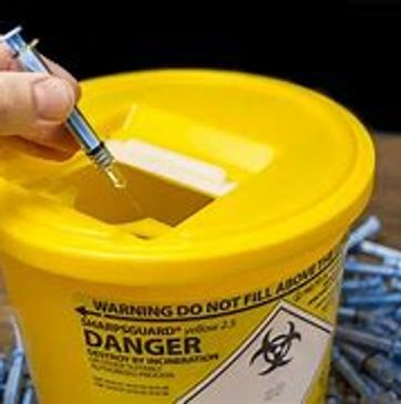 needle being put into a yellow sharps bin
