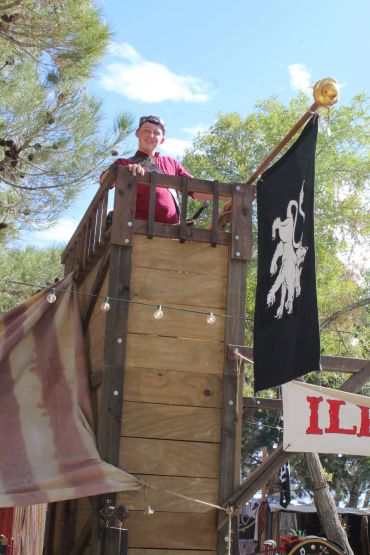 Man standing on wooden tower with black lion flag.
