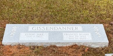 A gray granite marker headstone in a cemetery. 