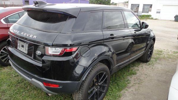 Black Range Rover SUV parked on grass near other vehicles.