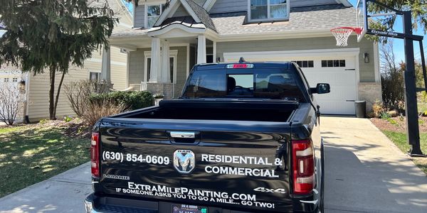 Black pickup truck with painting service advertisement parked in driveway.