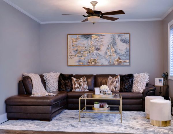 Cozy modern living room with a dark leather sectional and plush pillows.