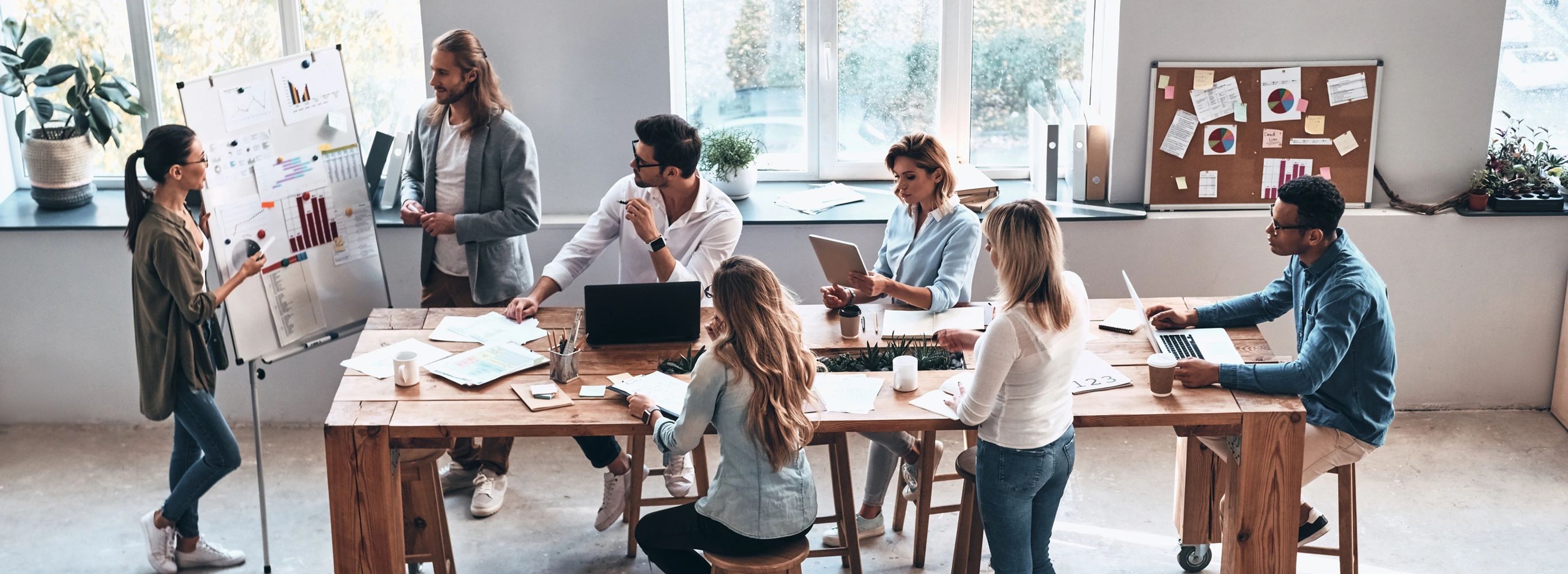 Group of people gathered around a conference table with presentations on a white board