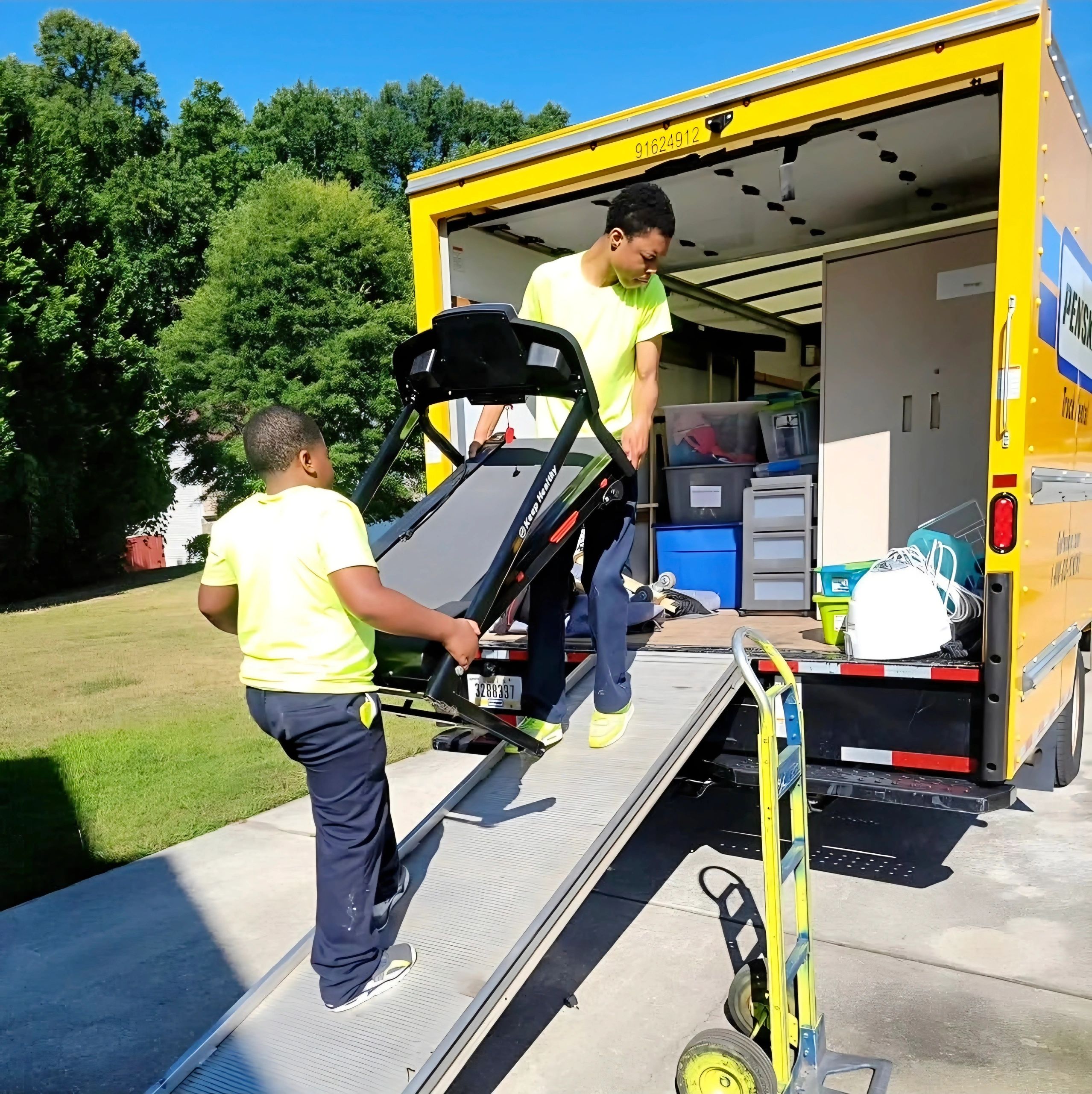 Fast Atlanta moving helpers safely unloading a heavy treadmill from a Penske truck.