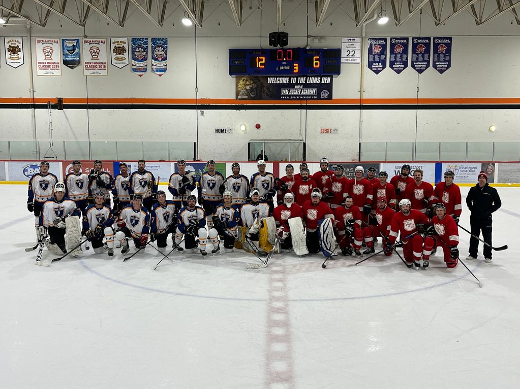 Two hockey teams posing together on the ice after a game.