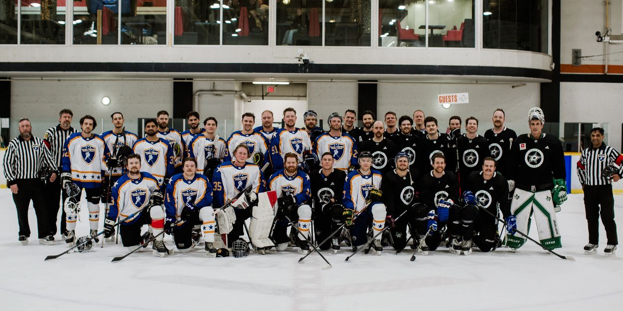 Two ice hockey teams posing together on the rink for a group photo.