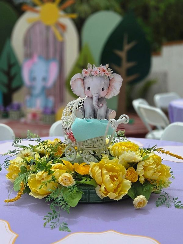 Adorable baby elephant figurine in a white carriage surrounded by vibrant yellow flowers.