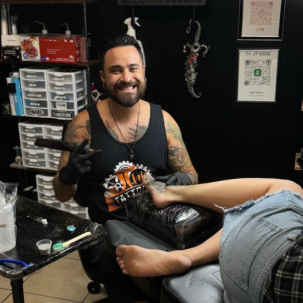 Tattoo artist tattooing a foot in a studio.