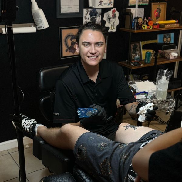 Tattoo artist working on a client's leg tattoo.