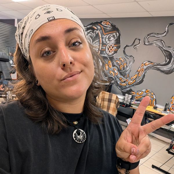 Woman making a peace sign with a graffiti octopus in the background.